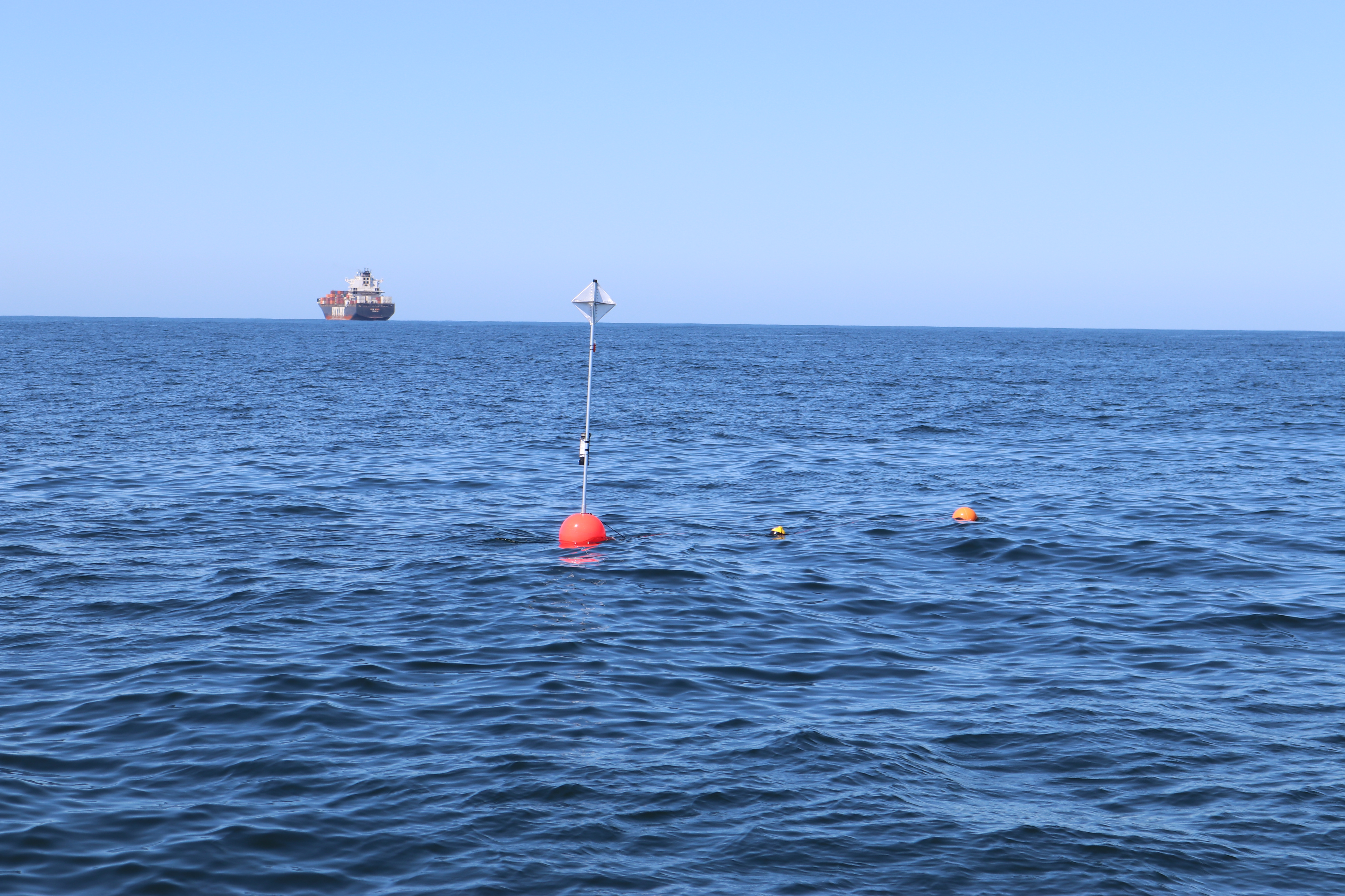 A drifting acoustic recorder floats offshore San Francisco with a large container ship in the background. Photo Credit Shannon Rankin, Southwest Fisheries Science Center, NOAA Fisheries.